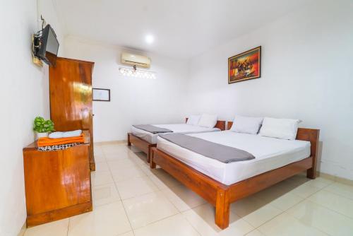a bedroom with two beds and a television in it at Griya Kulon Yogya in Jetis