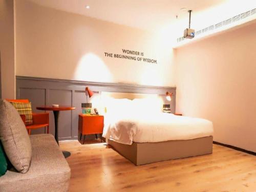 a bedroom with a bed with a sign on the wall at City Comfort Premier Hotel Xiaogan Anlu Railway Station Dongda Times Square in Xiaogan