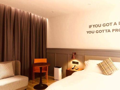 a hotel room with a bed and a chair at City Comfort Premier Hotel Xiaogan Anlu Railway Station Dongda Times Square in Xiaogan