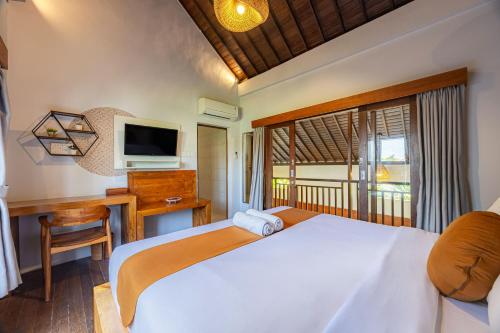 a bedroom with a bed and a desk and a television at Cove Belle Asana in Canggu