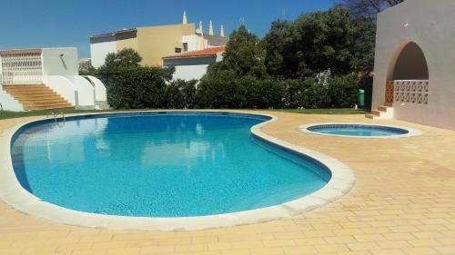 a large swimming pool in a yard with a building at Alta Oura in Albufeira
