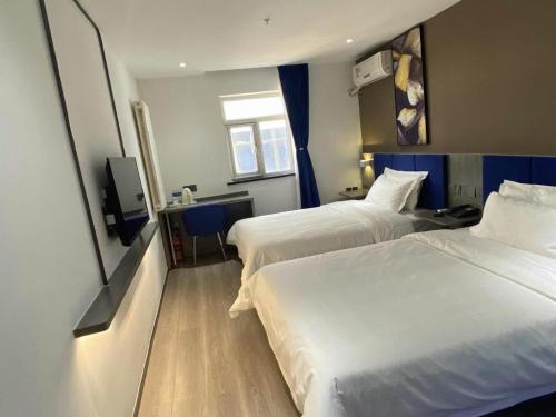 a hotel room with two beds and a television at 7 Days Inn Baoding Railway Station in Baoding