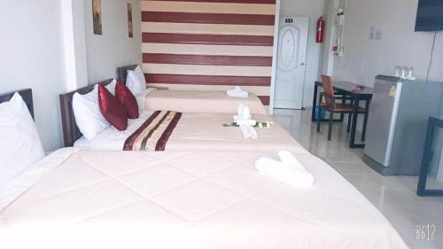 a bedroom with two beds with white sheets and red pillows at Rueangrat Hotel in Ranong