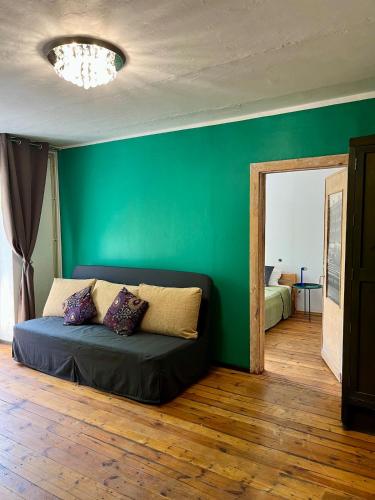 a green room with a couch and a green wall at Barinu Street Apartment in Liepāja