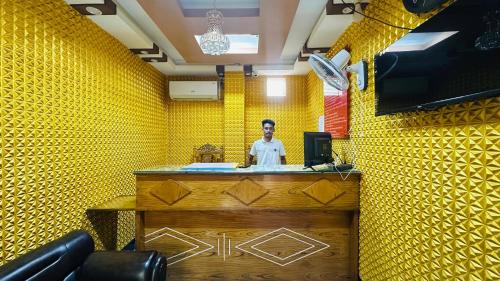 a man standing at a counter in a yellow room at Hotel zam Zam Residential in Dhaka