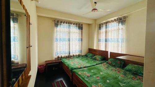 a bedroom with a green bed in a room with windows at Hotel zam Zam Residential in Dhaka