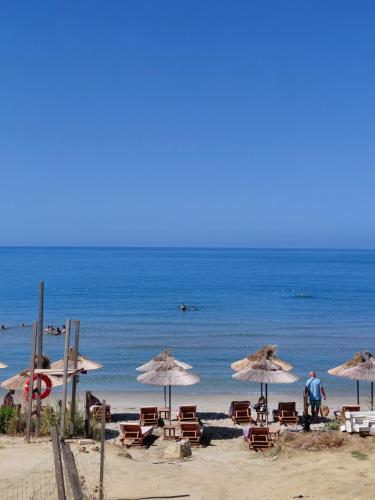 a beach with chairs and umbrellas and the ocean at Hotel Lalez Durres in Durrës