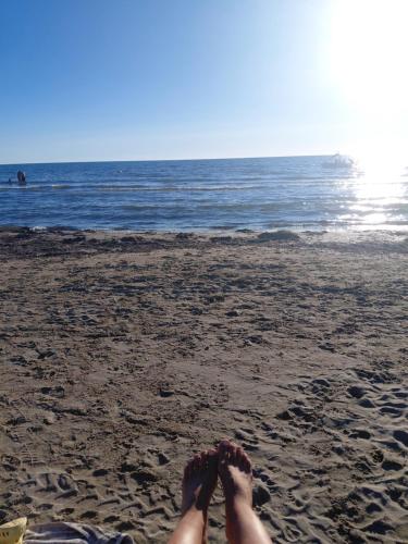a person laying on the beach with their feet in the sand at Hotel Lalez Durres in Durrës