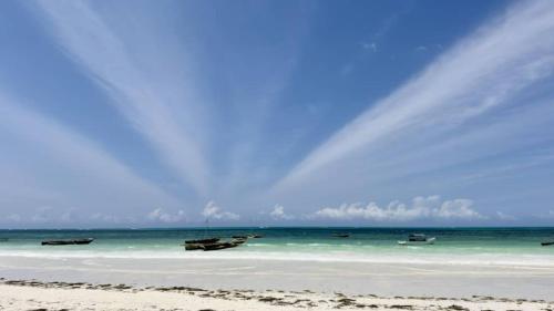 a group of boats on a beach with a rainbow in the sky at Zanzibar Lodge in Kiwengwa