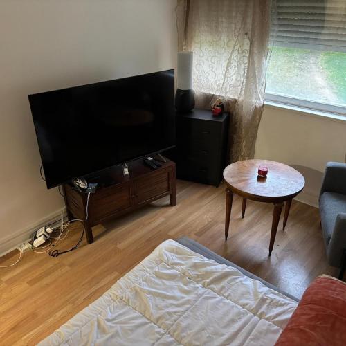 a living room with a flat screen tv and a table at charmant T2 avec balcon in Ris-Orangis