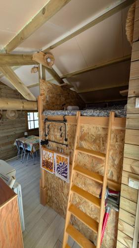 a room with a loft with a ladder and a table at Le chalet du bien-être in Vailhourles