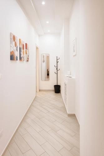 a hallway with white walls and white floors and paintings at Camere private Lingotto-Mirafiori Rooms in Turin