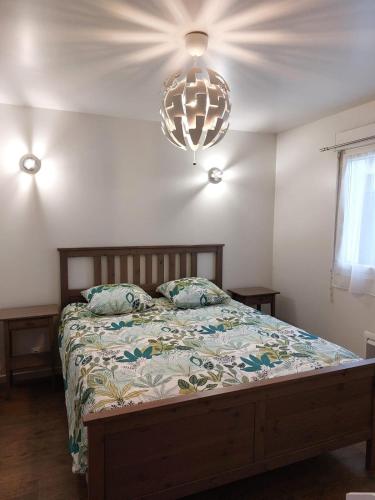 a bedroom with a bed and a chandelier at Jolie maison proche commodités, idéal vacances ou professionnels in Pleyben