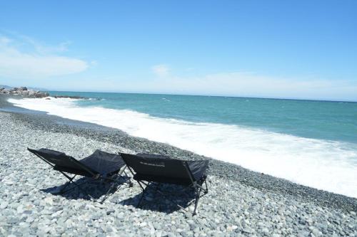 a couple of chairs sitting on a rocky beach at Private Rental 1 Minute Walk to the Sea 隠れ宿 波風の音 小田原の1棟貸切旅館 海まで徒歩1分 in Odawara
