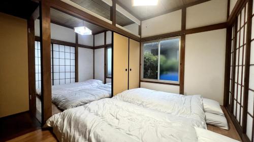 two beds in a room with windows at Private Rental 1 Minute Walk to the Sea 隠れ宿 波風の音 小田原の1棟貸切旅館 海まで徒歩1分 in Odawara