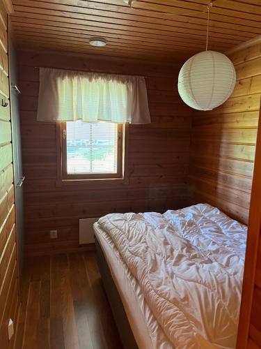 a bedroom with a bed in a wooden room with a window at Kärpänrinne A in Syöte