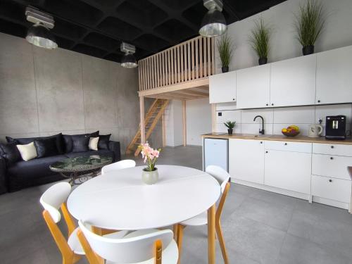 a kitchen and living room with a white table and chairs at Apartament Antresola in Ostróda
