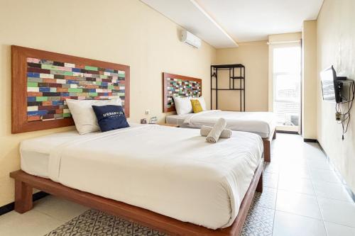 a bedroom with two beds and a tv at Urbanview Hotel Omah Anin Batu by RedDoorz in Tlekung