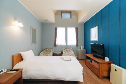 a bedroom with a white bed and a tv at DokiDoggie城ヶ島遊ケ崎BASE in Miura