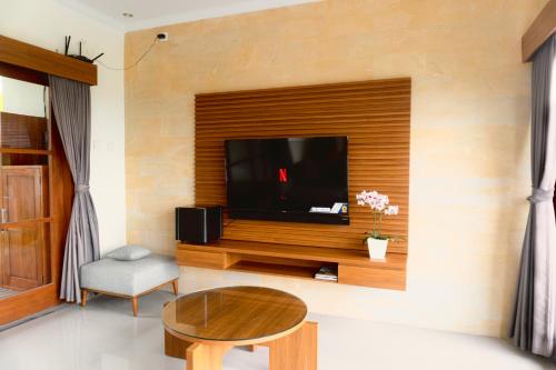 a living room with a tv on a wall at Ada Villa in Panji