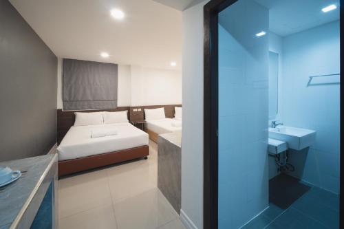 a bedroom with a bed and a bathroom with a sink at Grand Alpine Hotel in Bangkok