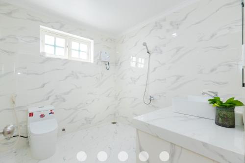a white bathroom with a shower and a toilet at Villas Checkin Hoa Giấy Gần Tháp Tam Thắng Bãi Sau in Vung Tau