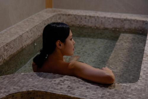 a woman sitting in a swimming pool at Stay Passport Airplane Guri in Guri