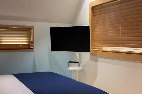 a bedroom with a bed and a tv and a window at Stay Passport Airplane Guri in Guri