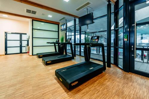 a gym with several treadmills in a room with windows at Coque Hotel in Luxembourg