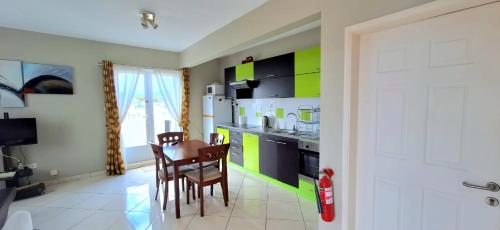 弗利康弗拉克Beautiful one bedroom apartment - Les Lauriers的厨房配有绿色和黑色的橱柜以及桌子和椅子
