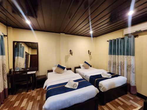 a room with two beds and a desk in it at Villa Le Tam Tam Boutique Hotel in Luang Prabang
