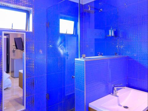a blue tiled bathroom with a sink and a shower at Skylight Guest Lodge in Johannesburg