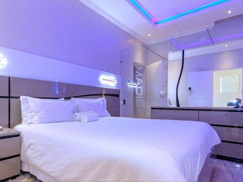a large white bed in a room with purple lighting at Skylight Guest Lodge in Johannesburg