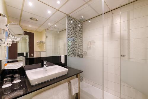 ein Bad mit einem Waschbecken und einer Dusche in der Unterkunft Novina Hotel Wöhrdersee Nürnberg City in Nürnberg