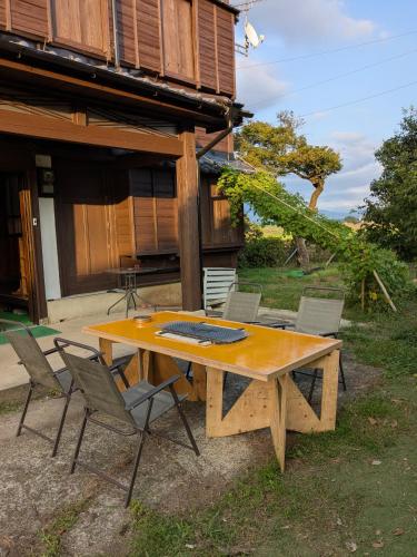 a wooden table with chairs in front of a house at 民泊サライ七城 in Kikuchi