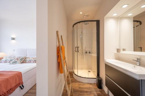 a bathroom with a bed and a shower and a sink at Au Louvre De Haan in De Haan