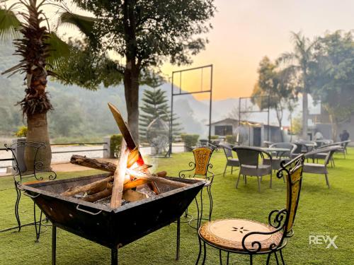 a fire pit in the grass with chairs and tables at Euphoric Resort ,Mohanchatti in Rishīkesh
