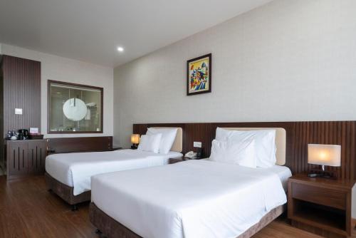 a hotel room with two beds and two lamps at Luxury6 Hotel in Móng Cái