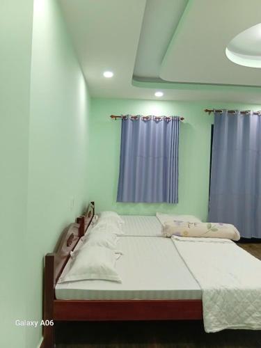 a large bed in a room with blue curtains at MOTEL Đồng Khởi in Giồng Tú Ðiền