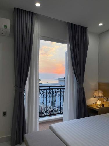 a bedroom with a window with a view of the ocean at Hotel Dell' Alba in Phú Quốc