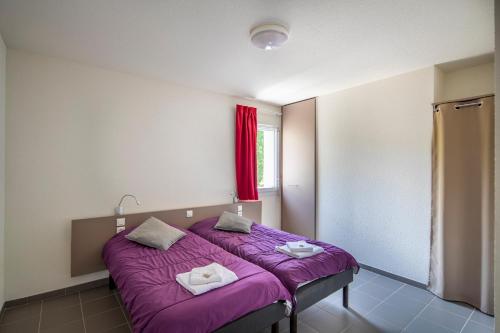 a bedroom with a purple bed with a window at Village Vacances passion La Buissière in Labeaume