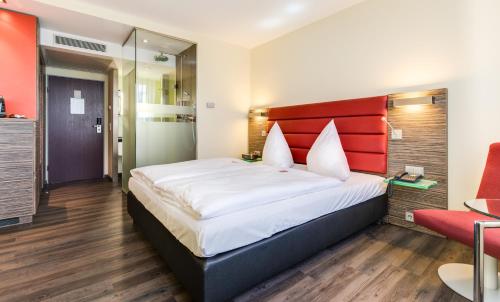 a bedroom with a large bed with a red headboard at Novina Hotel Wöhrdersee Nürnberg City in Nürnberg