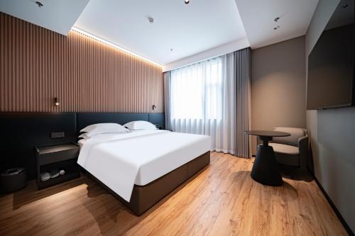 a bedroom with a large white bed and a table at Xihe Langyue Hotel Beijing Changying Tianjie Branch in Beijing