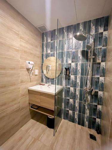 a bathroom with a sink and a shower with a mirror at Cham Charm Home Mui Ne in Mui Ne