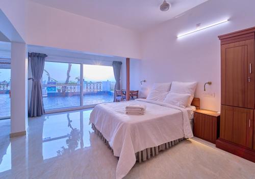 a bedroom with a bed and a large window at Alleppey Holiday Beach Resort By VOYE HOMES in Alleppey