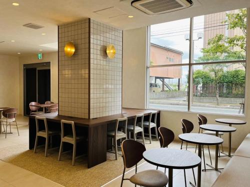 a restaurant with tables and chairs and a large window at Hotel Cross Base Tosu Station in Tosu