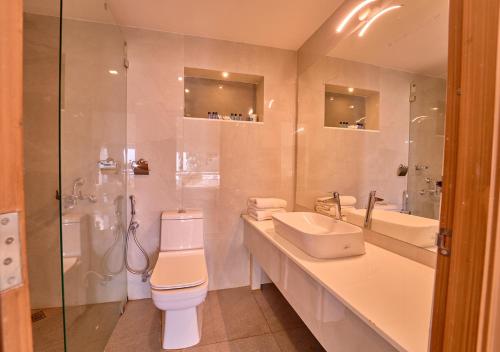 a bathroom with a toilet and a sink and a shower at Alleppey Holiday Beach Resort By VOYE HOMES in Alleppey