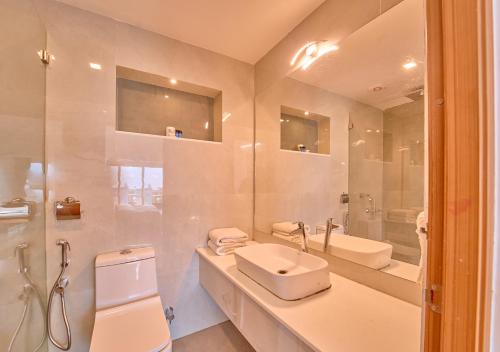 a white bathroom with a sink and a toilet at Alleppey Holiday Beach Resort By VOYE HOMES in Alleppey