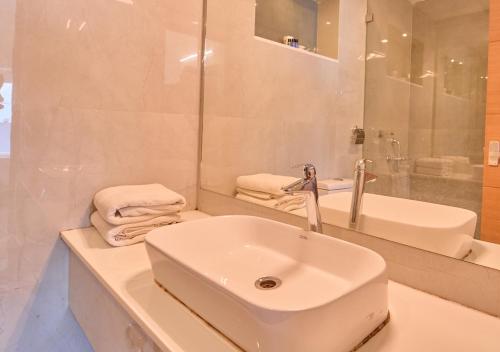 a white bathroom with a sink and a mirror at Alleppey Holiday Beach Resort By VOYE HOMES in Alleppey