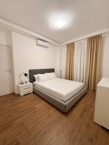 sypialnia z białym łóżkiem i drewnianą podłogą w obiekcie Casa Dell Angelo w mieście San Giuliano Milanese